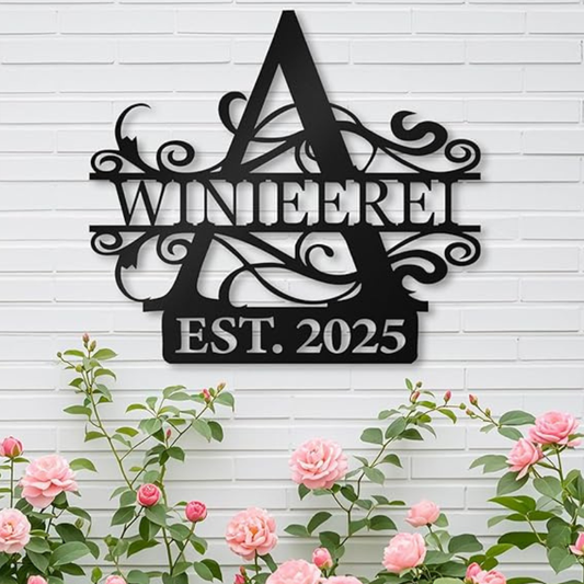 Schwarzes Monogramm-Schild mit geteiltem Buchstaben ‚M‘, graviertem Datum ‚2010‘ und dem Schriftzug ‚ESTABLISHED‘, montiert an einer Ziegelwand in einer Garage. Daneben ein geöffneter Werkzeugkasten mit graviertem Hammer und Schraubenschlüssel.